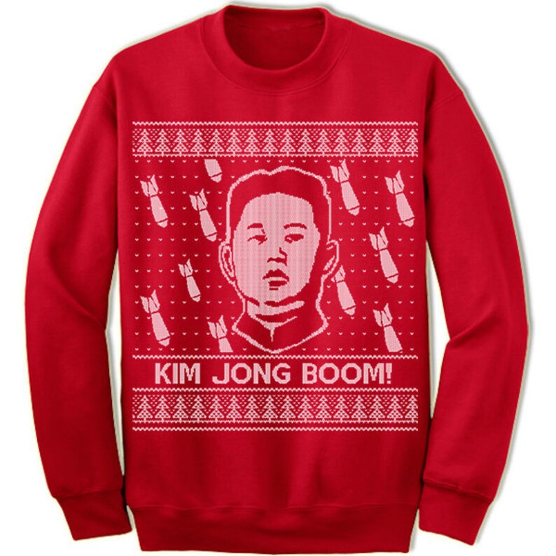 May include: Red Christmas sweater with a white knit pattern featuring a cartoon image of Kim Jong-un and the text "Kim Jong Boom!"