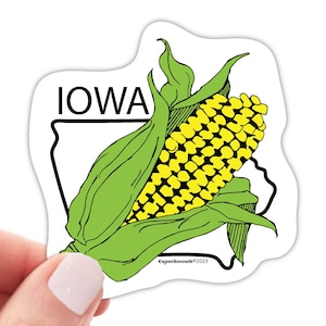 May include: A sticker featuring a yellow corn cob with green husks and the word "IOWA" in black text. The corn cob is inside the outline of the state of Iowa.
