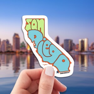 san diego travel luggage sticker, hand display, cityscape background