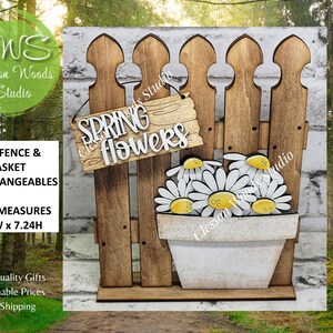 May include: A wooden decorative fence with a white brick background. The fence has a sign that reads "Spring Flowers". A white pot with daisies is in front of the fence. The fence measures 5.5"W x 7.24H.