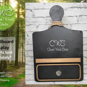 May include: Black wooden breadboard display stand with a shelf and a hole for hanging. The stand has a gold-colored trim and the text "CWS Clesson Woods Studio" is printed on the front.