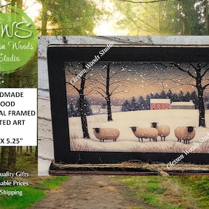 May include: Handmade wood framed art print featuring a winter scene with sheep, trees, and a red barn. The black frame measures 7.5 x 5.25 inches. The artwork is from Clesson Woods Studio.