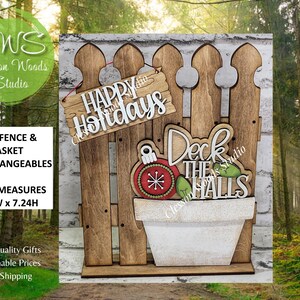 May include: Wooden fence with a white brick background, featuring a sign that says "Happy Holidays" and a pot with a Christmas ornament and the words "Deck the Halls." The fence measures 5.5"W x 7.24H.