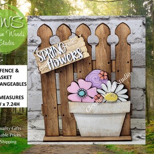 May include: Wooden spring-themed decoration featuring a brown picket fence with a sign that reads "Spring Flowers." A white flower pot holds pink, purple, and white flowers. The fence measures 5.5"W x 7.24"H.