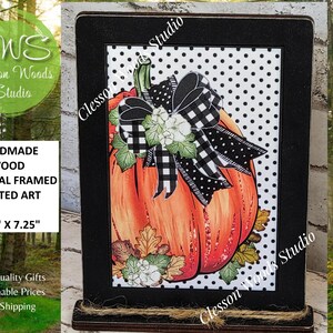 May include: Handmade wood framed art featuring a vibrant orange pumpkin with a black and white checkered bow. The artwork is 5.50" x 7.25" and set against a white polka dot background. The frame is black, and the piece is from Clesson Woods Studio.