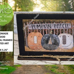 May include: Handmade wood framed art featuring three whimsical pumpkins in a pumpkin patch scene. The artwork is 7.5" x 5.25" and includes the text "Pumpkin Patch". The frame is black with a rustic twine accent.