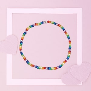 May include: A colourful beaded bracelet with silver beads and a rainbow of colours, including red, orange, yellow, green, blue, and purple.