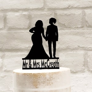 May include: Black silhouette cake topper of a bride and groom holding hands with the text "Mr & Mrs McCreath" below.