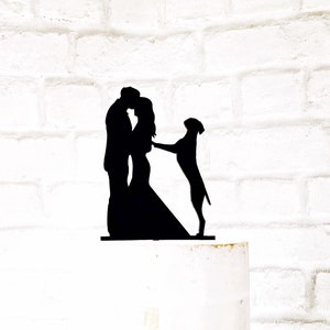 May include: Black silhouette cake topper of a couple kissing with a dog standing beside them. The topper is made of acrylic and is perfect for a wedding or anniversary cake.