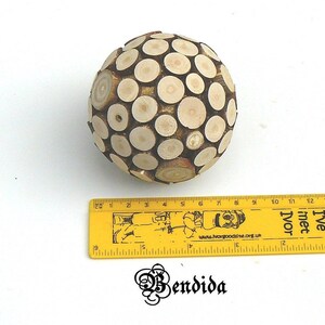May include: A wooden sphere made of small, round pieces of wood. The sphere is about 6 inches in diameter and is a light brown color.