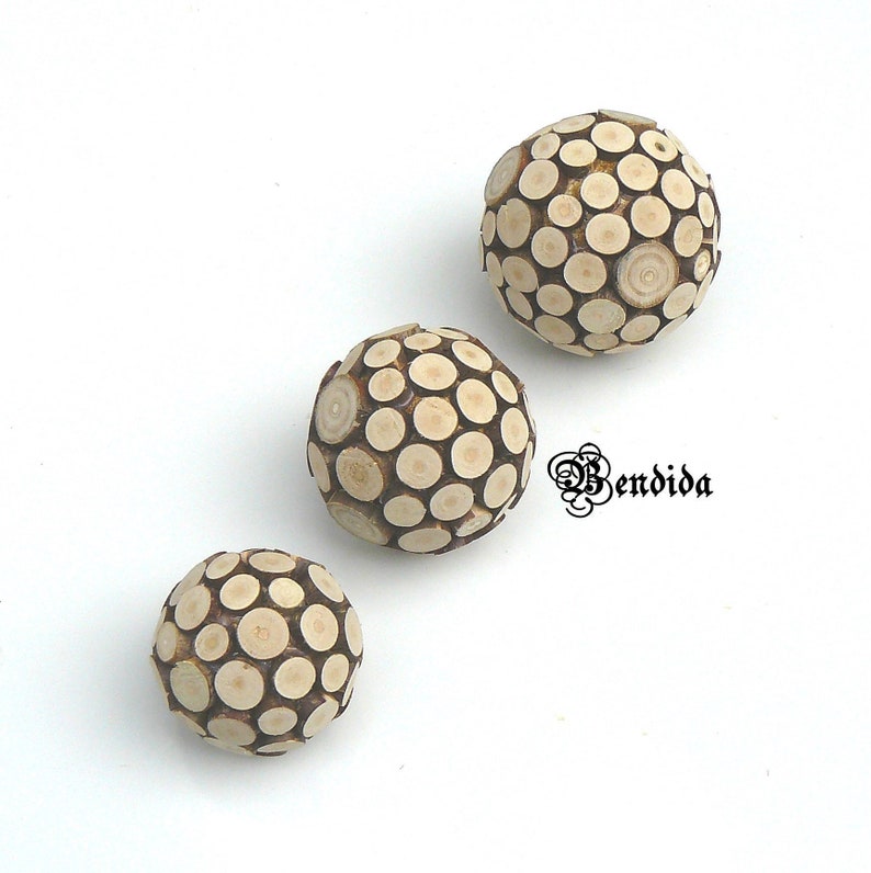 May include: Three wooden spheres made of small, round pieces of wood. The spheres are different sizes and are arranged in a row from largest to smallest.
