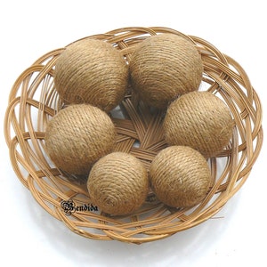 May include: Six brown twine balls in a woven wicker basket. The balls are made of natural twine and are a natural brown color.