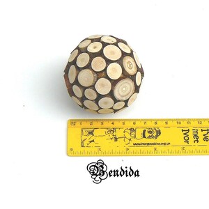May include: A wooden sphere ornament made of small, round pieces of wood. The sphere is about 6 inches in diameter and has a natural wood color.