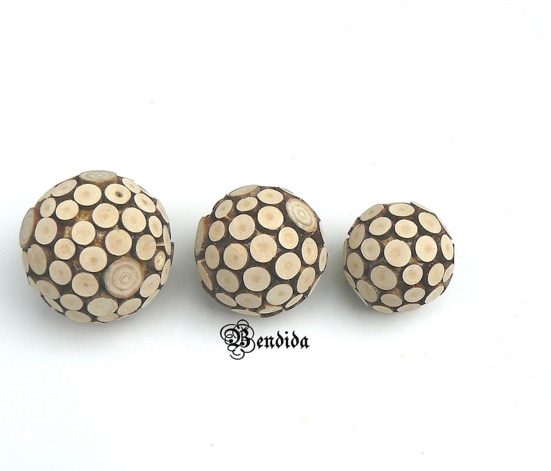 May include: Three wooden spheres made of small, round, wooden pieces. The spheres are different sizes and are arranged in a row from largest to smallest.