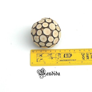 May include: A wooden sphere ornament made of small, round pieces of wood. The sphere is about 6 inches in diameter and is a light brown color.