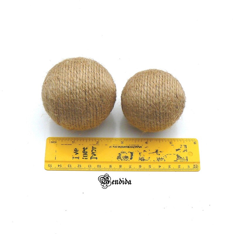 May include: Two brown jute twine balls, one larger than the other, on a white surface with a yellow ruler for scale. The larger ball is approximately 2 inches in diameter, and the smaller ball is approximately 1.5 inches in diameter.
