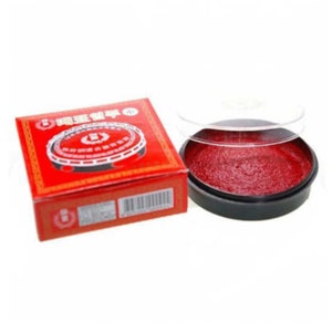 May include: A red ink pad in a clear plastic container with a black lid. The ink pad is labeled in Chinese characters.