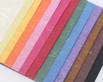 Könnte beinhalten: Ein Set mit 15 Blättern strukturiertem Papier in verschiedenen Farben, darunter Weiß, Gelb, Orange, Rosa, Rot, Grün, Blau, Lila, Braun und Schwarz.