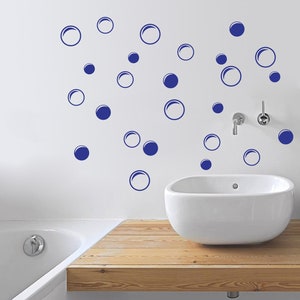 May include: A white bathroom with a white bathtub and a white sink. The wall is decorated with blue circle stickers that look like bubbles.