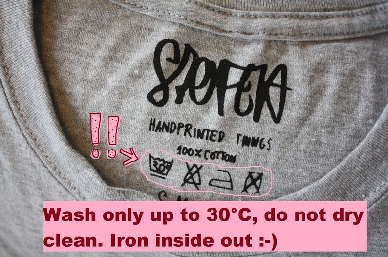 May include: A gray t-shirt with a black care label that says "SOFEA HANDPRINTED THINGS 100% COTTON". The care label includes symbols for machine washing at 30 degrees Celsius, no bleaching, ironing, and no tumble drying. The text below the image says "Wash only up to 30&deg;C, do not dry clean. Iron inside out :-) "