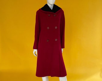 Puede incluir: Un abrigo largo de lana roja con cuello negro y botones de doble botonadura. El abrigo está en un maniquí blanco sobre un fondo amarillo.