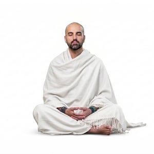 Puede incluir: Una persona en posición meditativa, sentada con las piernas cruzadas sobre un fondo blanco. Está envuelta en un chal blanco, con los ojos cerrados y las manos en un gesto meditativo. La imagen transmite una sensación de paz y tranquilidad.