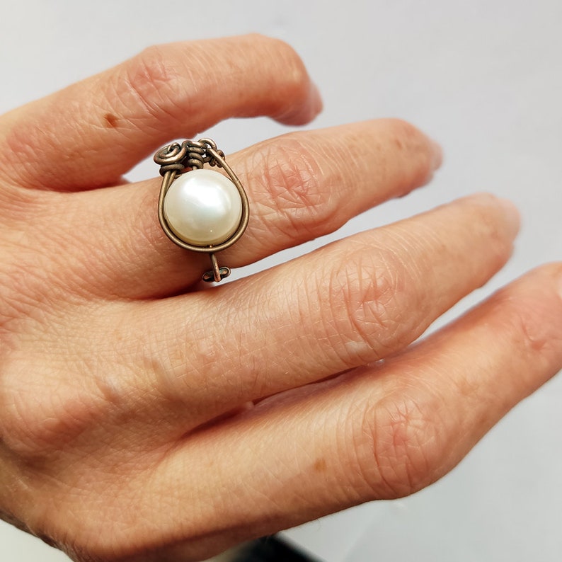 May include: A ring with a white pearl set in a bronze wire design.