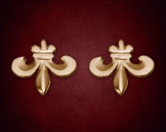 Könnte beinhalten: Ein Paar goldfarbene Fleur-de-lis-Ohrringe. Die Ohrringe sind aus Metall und haben ein detailliertes Design.