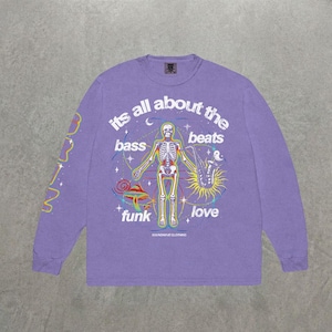 Puede incluir: Una camiseta de manga larga de color morado claro con un gráfico central de un esqueleto tocando el saxofón, rodeado de estrellas, un hongo y el texto "its all about the bass beats funk love" y "SOUNDWAVE CLOTHING" impreso en blanco.