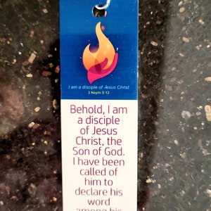 May include: A blue and white bookmark with a flame design and the text "I am a disciple of Jesus Christ 3 Nephi 5-13". The bookmark also includes the text "Behold, I am a disciple of Jesus Christ, the Son of God. I have been called of him to declare his word among his people, that they might have everlasting life."