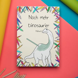 May include: A colouring book with a colourful border of pencils. The cover features a cartoon dinosaur with the title "Noch mehr Dinosaurier" and the word "Malbuch".