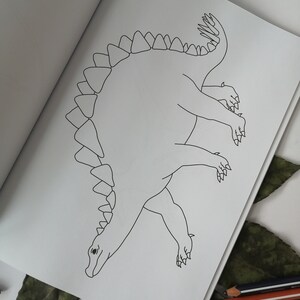 May include: A black and white line drawing of a Stegosaurus dinosaur on a white page. The dinosaur is viewed from above, with its distinctive plates along its back and a long tail. The image is from a coloring book.