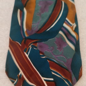 May include: A teal blue silk tie with a geometric pattern in shades of brown, white, and purple.
