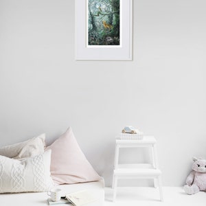 May include: A framed art print featuring a forest scene with a deer, bird, and badger under a full moon. The artwork is in a white frame, displayed on a white wall. The room includes a mattress, pillows, a small white step stool, and a stuffed animal.