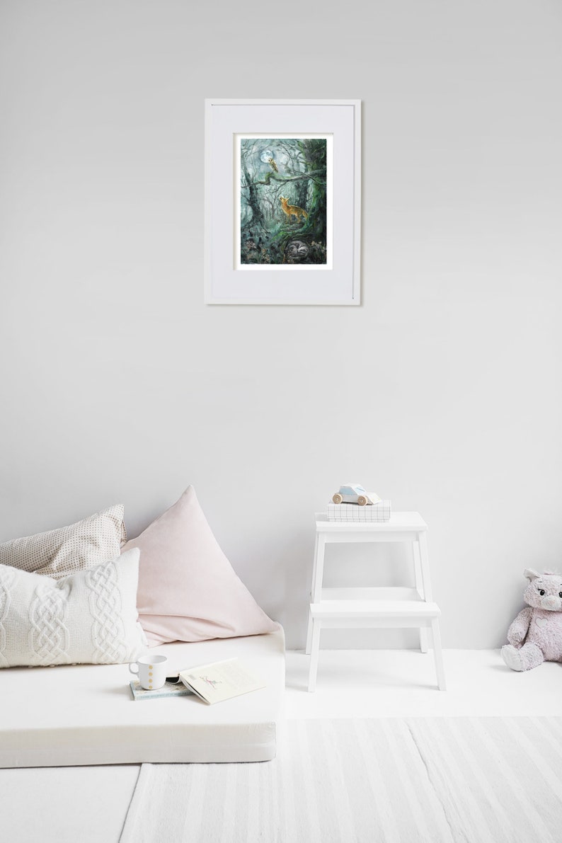 May include: A framed art print featuring a forest scene with a deer, bird, and badger under a full moon. The artwork is in a white frame, displayed on a white wall. The room includes a mattress, pillows, a small white step stool, and a stuffed animal.