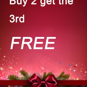 May include: A festive promotional graphic with a gradient red background. White text reads "Buy 2 get the 3rd FREE". A red ribbon and bow with pine branches and sparkling confetti complete the design.