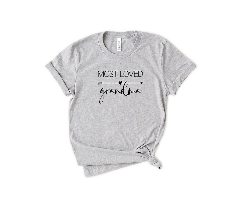 May include: Gray t-shirt with black text that reads "Most Loved Grandma" with an arrow and heart graphic.