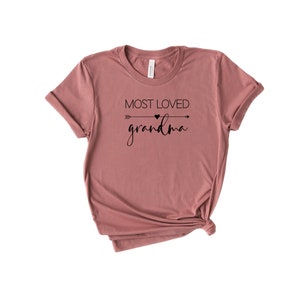 May include: A mauve t-shirt with a black arrow and heart graphic and the text "Most Loved Grandma".