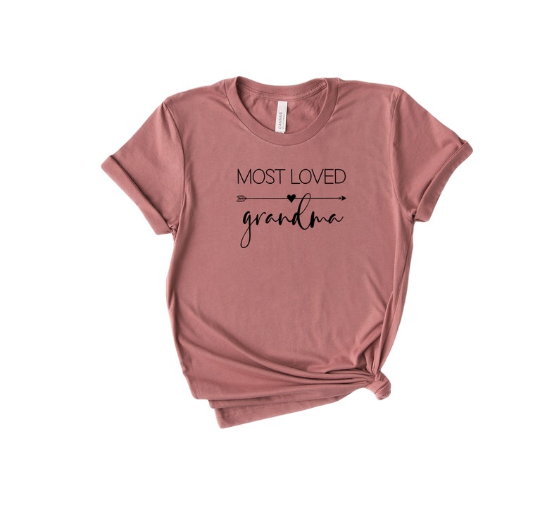 May include: A mauve t-shirt with a black arrow and heart graphic and the text "Most Loved Grandma".