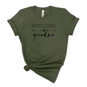 May include: A green t-shirt with the text "MOST LOVED grandma" in black lettering with an arrow and heart graphic.
