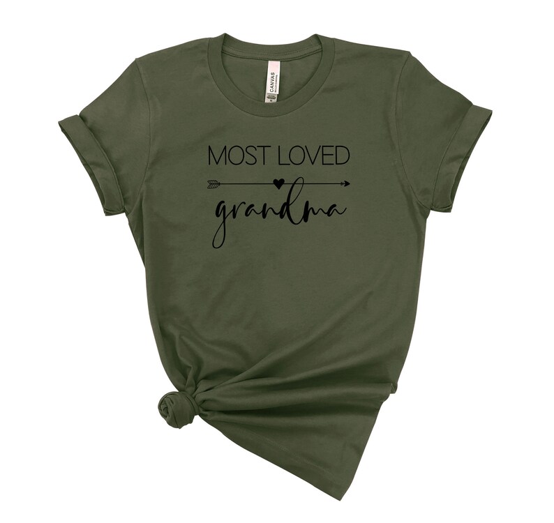 May include: A green t-shirt with the text "MOST LOVED grandma" in black lettering with an arrow and heart graphic.