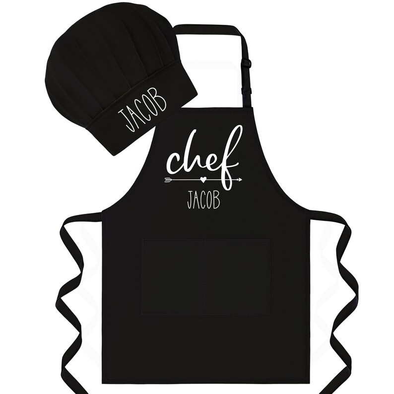 Puede incluir: Conjunto de delantal y gorro de chef negro con el texto "chef" y una flecha con un coraz&oacute;n sobre el nombre "Jacob".
