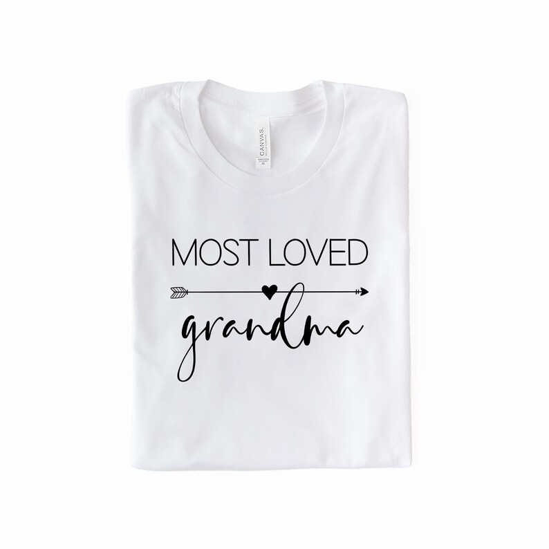 May include: White t-shirt with black text that reads "Most Loved Grandma" with an arrow and heart graphic.