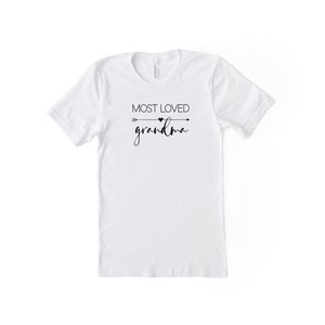 May include: White t-shirt with black text that reads "MOST LOVED grandma" with a small heart and arrow graphic.