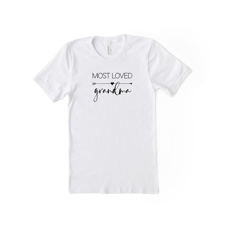 May include: White t-shirt with black text that reads "MOST LOVED grandma" with a small heart and arrow graphic.