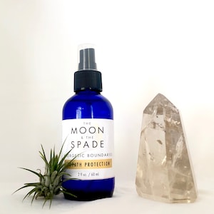 May include: A blue glass bottle with a black spray top and a white label that reads "THE MOON & THE SPADE" and "ENERGETIC BOUNDARIES PATH PROTECTION 2 fl oz. / 60 ml".