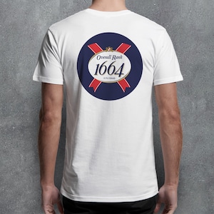 May include: White t-shirt with a navy blue circular graphic on the back. The graphic features the text "Overall Rank 1664" in a gold oval, surrounded by red ribbons and a navy blue background. The shirt is made of a soft material.
