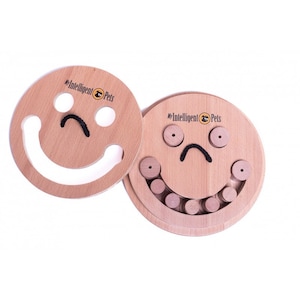 May include: A wooden dog puzzle toy shaped like a smiley face. The toy has a removable top with a hole in the middle. The bottom of the toy has a series of holes around the edge, and the top has a series of wooden pegs that fit into the holes. The toy is labeled "My Intelligent Pets".