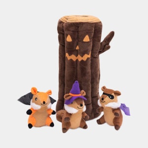May include: A Halloween-themed plush toy set featuring a brown tree trunk with a jack-o'-lantern face, and three plush squirrels in costumes. One squirrel is dressed as a bat, another as a witch, and the third as a superhero.