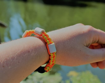 May include: A yellow and orange braided bracelet with white plastic beads. The bracelet is worn on a person's wrist.